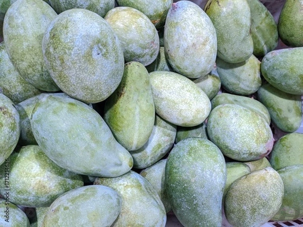 Fototapeta A full-frame, overhead shot of a large pile of fresh, green mangoes.