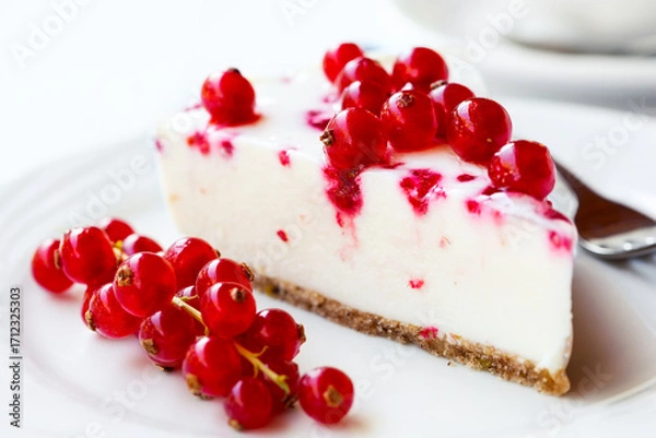 Fototapeta A slice of red currant cheesecake, served on a white plate.