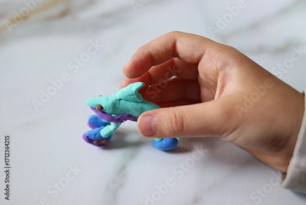 Fototapeta A plasticine figure made by a child in the shape of a shark in children's hands, close-up.