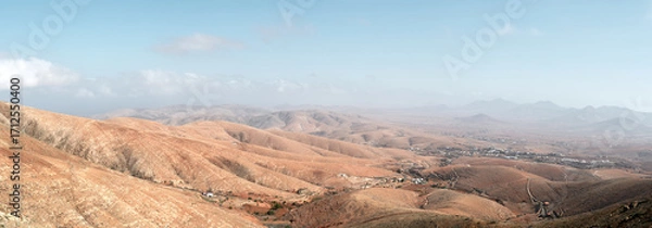 Fototapeta Panoramic view from Guise and Ayose viewpoint in Fuerteventura. Arid mountains and valleys extend under a clear blue sky, showing the volcanic landscape of the Canary Islands.