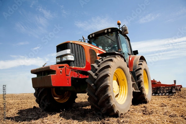 Fototapeta Tractor plowing the field in autumn