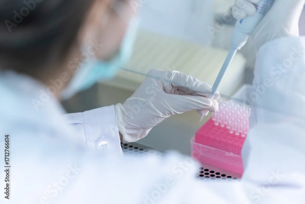 Fototapeta Laboratory technician conducts experiments with test tubes and microscope in a modern research facility