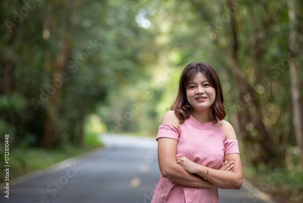 Obraz Portrait of a beautiful young woman walking on a road through a lush forest. Portrait of Asian.