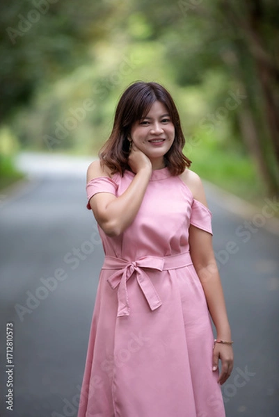 Obraz Portrait of a beautiful young woman walking on a road through a lush forest. Portrait of Asian.