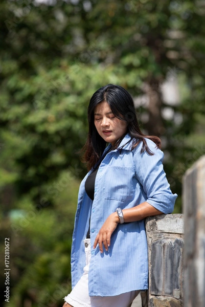 Obraz Portrait of a beautiful young woman walking on a road through a lush forest. Portrait of Asian.