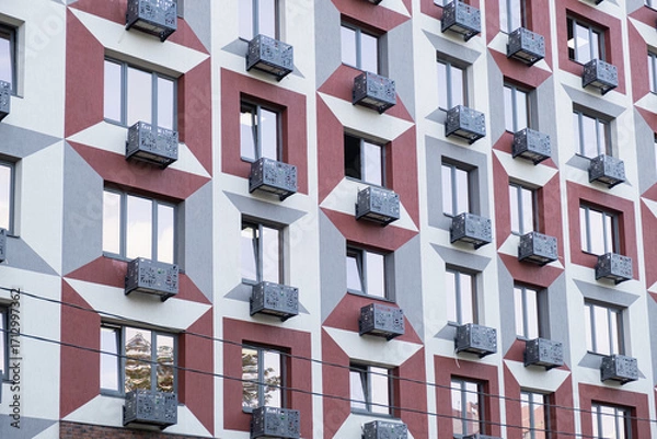Fototapeta Modern low-cost residential building with repeating windows and small decorative balconies, representing affordable housing in dense city neighborhood.