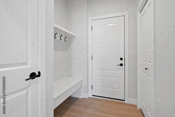 Fototapeta White door with a black handle and a white bench in front of it