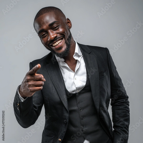 Fototapeta Confident businessman portrait in elegant black tailored suit and white shirt, smiling with pointing gesture, isolated light grey background corporate style