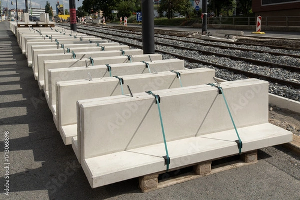 Fototapeta stack of pre-cast concrete blocks is ready for installation on a road next to tram tracks  ongoing construction work on the tramway infrastructure.
