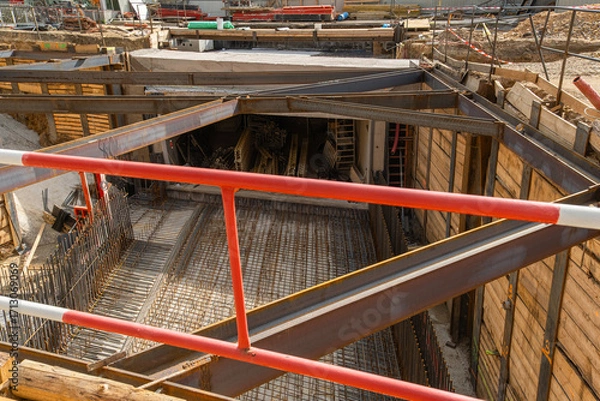 Fototapeta deep excavation at a construction site reveals the groundwork for a foundation, featuring a dense grid of steel rebar on a concrete slab