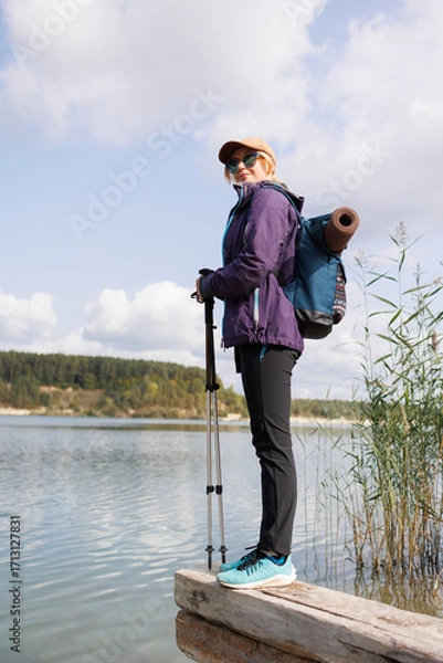 Fototapeta Female traveler standing on log by lake