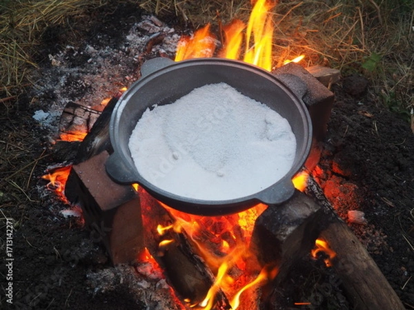 Fototapeta kettle on fire The first firing of the cauldron over an open fire with table salt