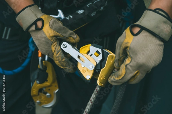 Fototapeta Firefighter and rescuer putting on harness, carabiners, and rappelling equipment to practice rappelling down a multi-story building.