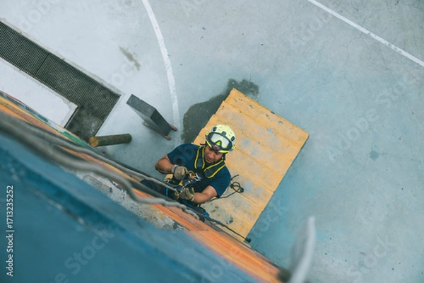 Fototapeta 
Firefighter rescuer descending a massive wall using a rappelling device in a multi-story building, wearing protective gear such as a helmet, harness, and carabiners.