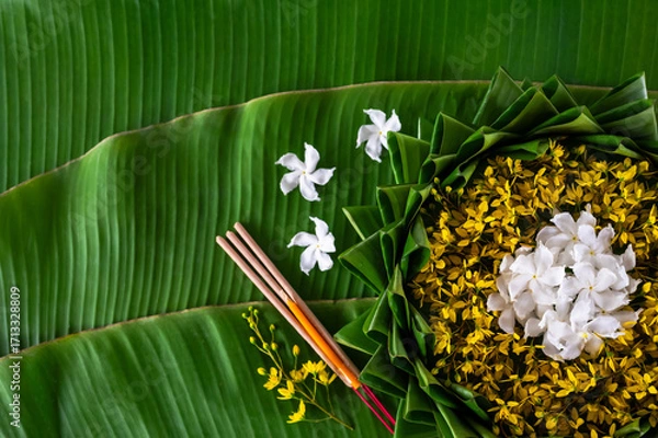 Fototapeta Krathong decorates with flowers that have blurred focus of 3 incense sticks and candle put on banana leaf for Loy Krathong festival.