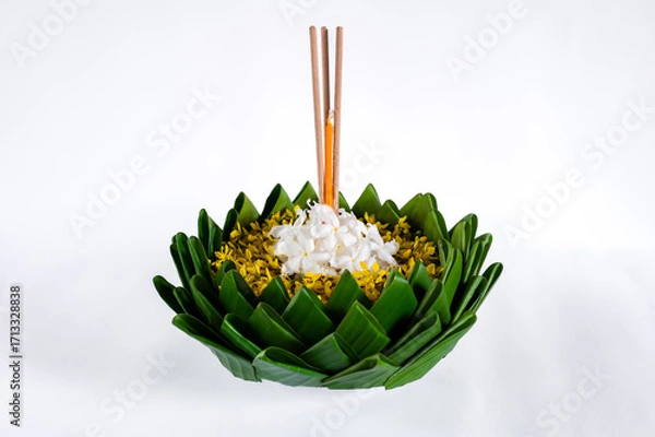 Fototapeta Banana leaf Krathong that have 3 incense sticks and candle decorates with flowers for Loy Krathong festival isolated on white paper background.