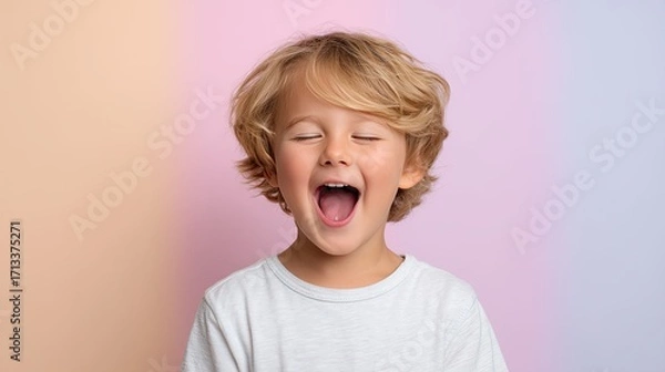 Fototapeta Closeup of little boy giggling uncontrollably, showcasing pure joy and happiness against soft pastel background. His playful expression captures essence of childhood delight
