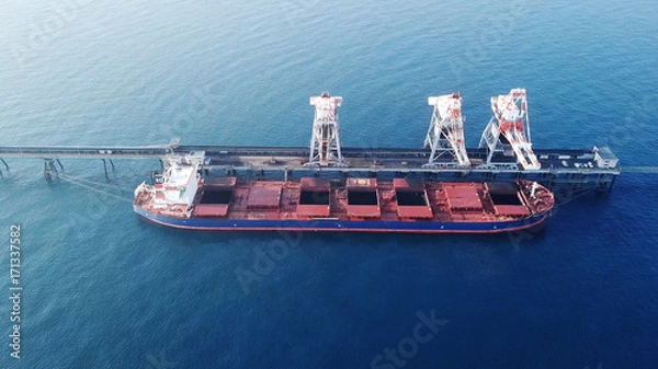 Obraz Large bulk carrier ship docking - Unloading coal ship by cranes on the power station dock