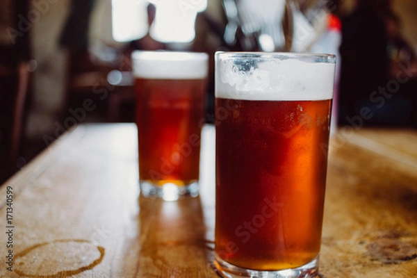 Fototapeta An english ale bitter beer pint on a wooden table in a pub in UK