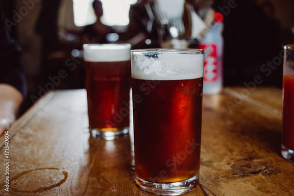 Fototapeta An english ale bitter beer pint on a wooden table in a pub in UK