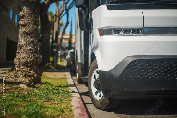Fototapeta White electric truck in the city. Closeup on headlight.