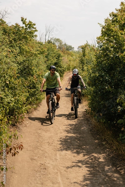 Fototapeta Cyclists enjoying an outdoor trail surrounded by nature, trees, and natural surroundings