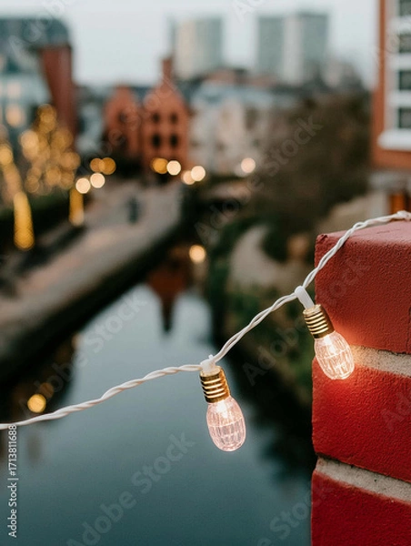 Fototapeta String of light bulbs hanging from a red brick wall. the string is strung across the wall, with the light bulbs facing towards the right side of the image.
