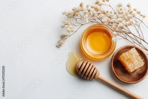 Fototapeta Honey jar honeycomb dipper  dried flowers are arranged on a white background