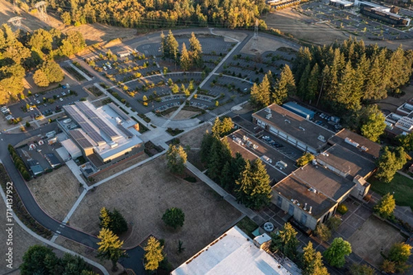 Fototapeta Aerial drone picture of a modern college building in Oregon City with rooftop solar panels, showcasing renewable energy technology and sustainable architecture in an academic campus setting
