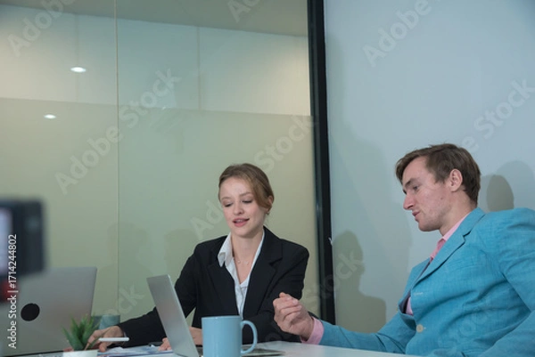 Fototapeta Professional individuals engage in business meeting, discussing ideas and strategies. atmosphere is focused and collaborative, showcasing teamwork in modern office setting