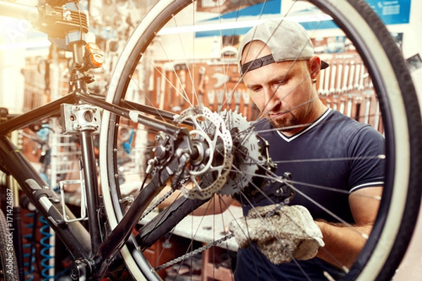 Fototapeta Bicycle mechanic in a workshop in the repair process