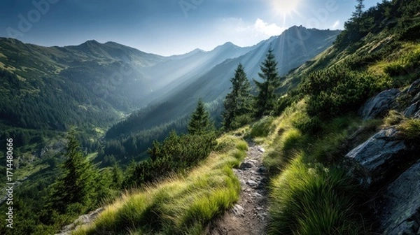 Fototapeta Mountain Trail in Sunlight: A winding trail leads the eye through a vibrant, sun-drenched mountain landscape, with rolling hills and peaks bathed in warm sunlight.