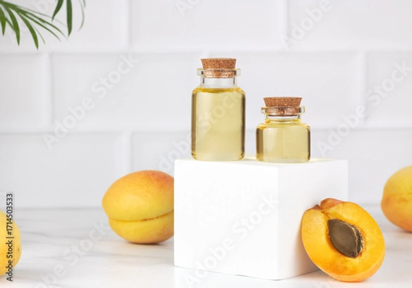 Fototapeta Apricot oil in glass bottles with fresh apricots on white background. Natural skincare, aromatherapy concept. Copy space