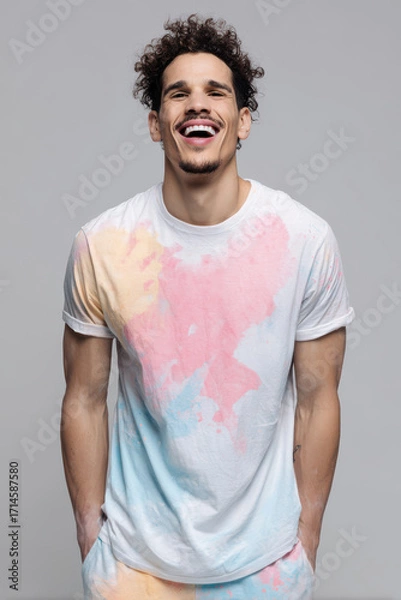 Fototapeta joyful man wearing ultrabright colorful tshirt stands against soft gray background