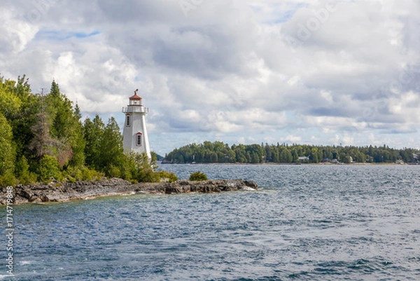 Obraz Charming view of Big Tub Harbour Lighthouse in Tobermory, Ontario, featuring serene waters and lush greenery.