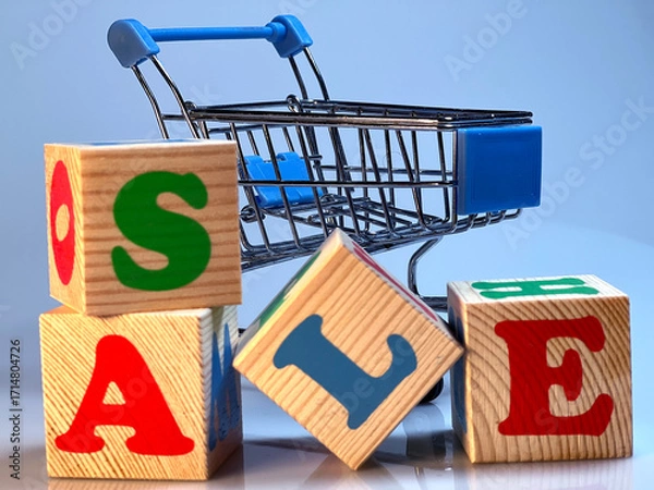 Fototapeta A shopping cart is filled with wooden blocks that spell out the word "sale".