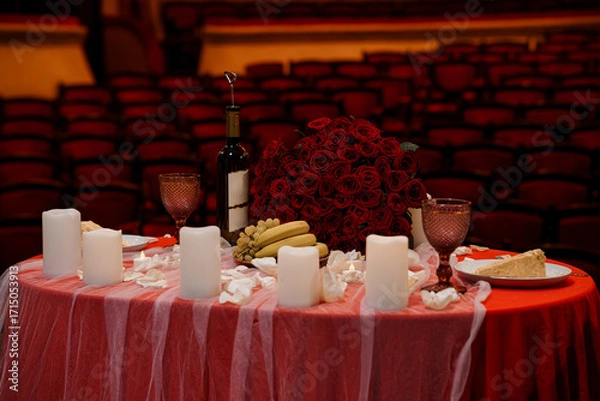 Fototapeta Romantic Table Setting with Roses, Wine and Dessert in Theater's Empty Red Seating Rows. Dramatic Still Life Composition, Dark Aesthetic