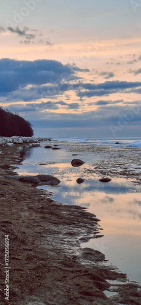 Obraz Peaceful scene of ice floes drifting in calm ocean waters with stunning sunset sky. Reflective water surface captures colorful clouds, evoking serenity and tranquility. Vertical photo