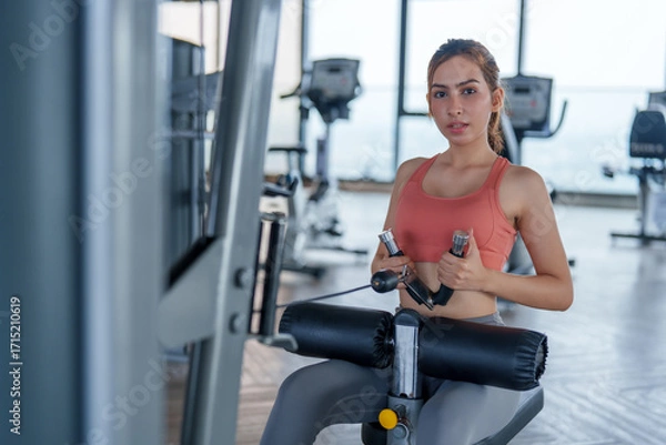 Fototapeta Woman engages in focused workout at modern gym, showcasing her commitment to fitness and self care. This exercise routine promotes wellness and enhances overall health