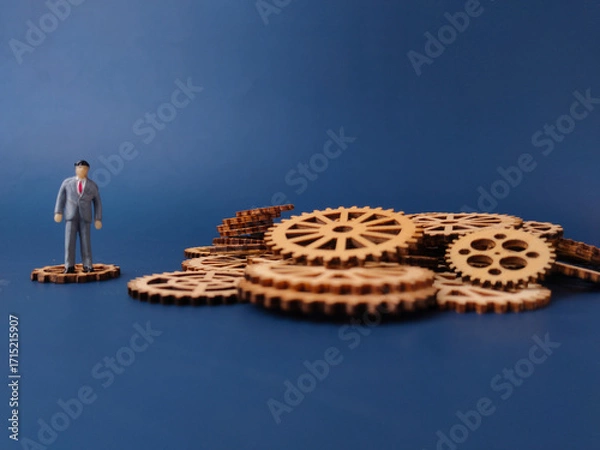 Fototapeta The miniature figure on a single gear represents an individual or a small part of a larger operation