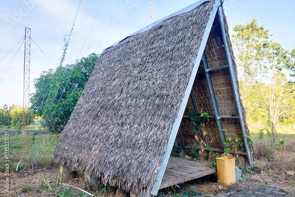 Fototapeta Traditional open-sided hut with an A-frame structure and a palm leaf thatched roof.