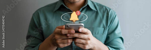 Fototapeta Man checks phone with glowing notification bell icon symbolizing important alerts and app updates, creating a sense of urgency and engagement