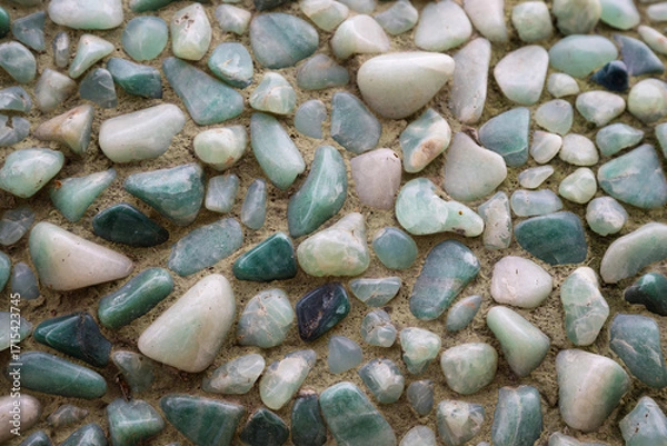Fototapeta 2023-12-31 VARIOUS SMOOTH COLORFUL ROCKS SET IN CONCRETE AS A BACKGROUND