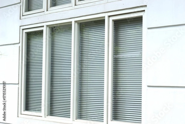 Fototapeta Window with closed blinds in a white wall, representing privacy and modern architecture