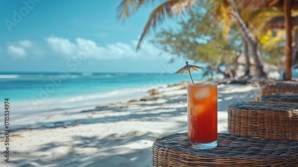 Fototapeta A tropical drink with a paper umbrella sits on a wicker table at a beach. The ocean and palm trees are visible in the background. AI.