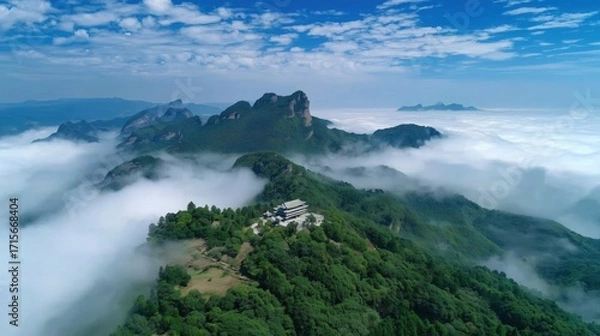 Fototapeta Aerial View of Serene Mountain Landscape Surrounded by Ethereal Clouds under Bright Blue Sky