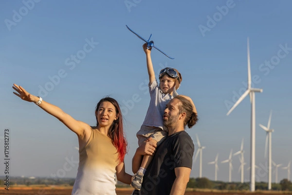 Fototapeta Family with son walking on field on wind farm. Happy Family and son playing at the Wind turbines generating electricity. Family time together.