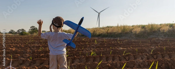 Fototapeta Boy Playing on field on wind farm. Happy Boy playing at the Wind turbines generating electricity. Family time together.