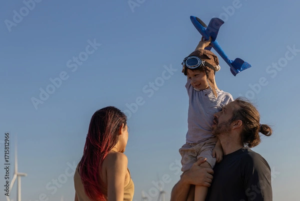 Fototapeta Family with son walking on field on wind farm. Happy Family and son playing at the Wind turbines generating electricity. Family time together.