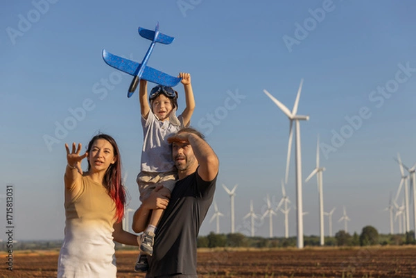 Fototapeta Family with son walking on field on wind farm. Happy Family and son playing at the Wind turbines generating electricity. Family time together.